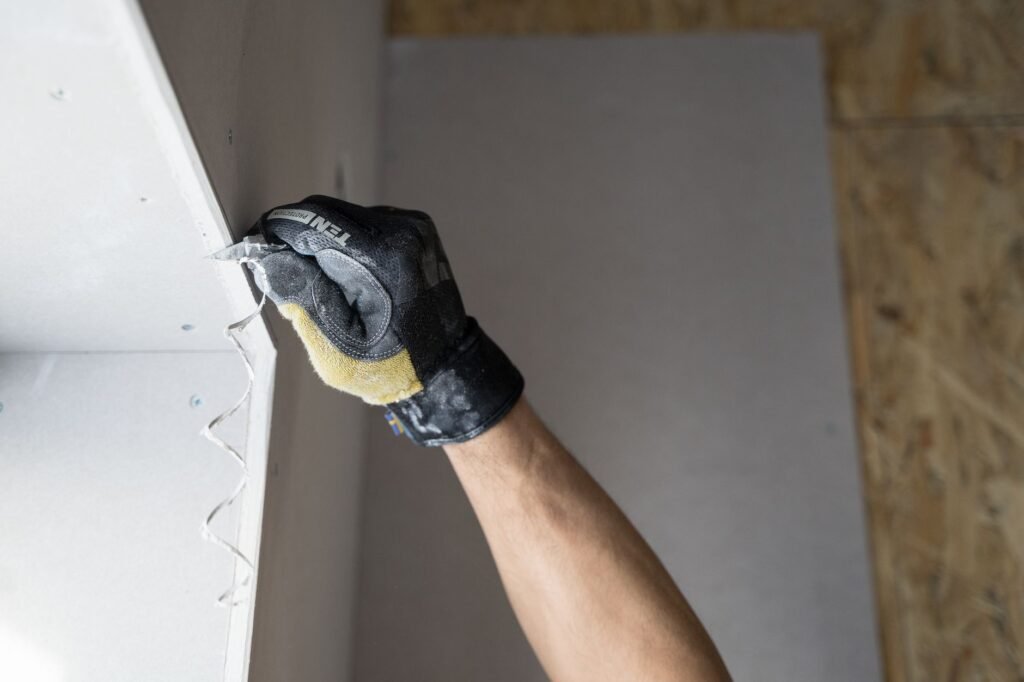 Gloved hand patching a wall after rodent damage